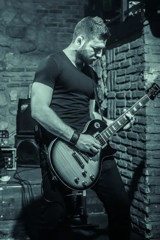 Alex Moudatsos playing electric guitar on stage.